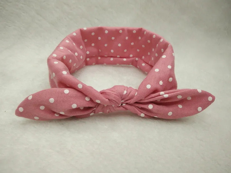Set of 9 cotton jersey baby headbands in various colours with rabbit ears on white background