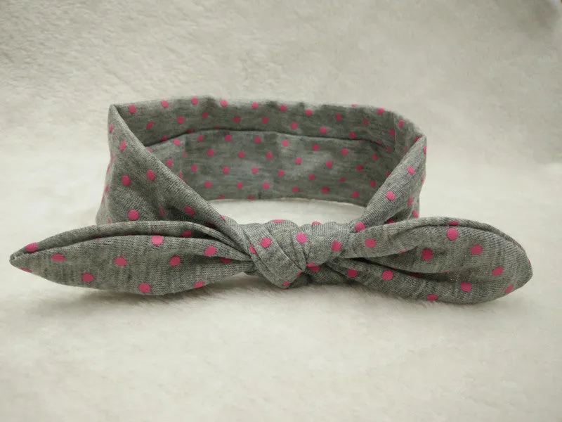 Set of 9 cotton jersey baby headbands in various colours with rabbit ears on white background
