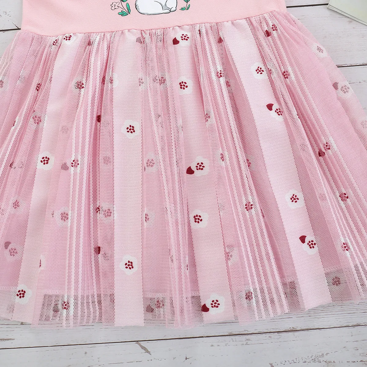 Pink cotton girls princess dress with cartoon rabbit print and mesh overlay on plain background