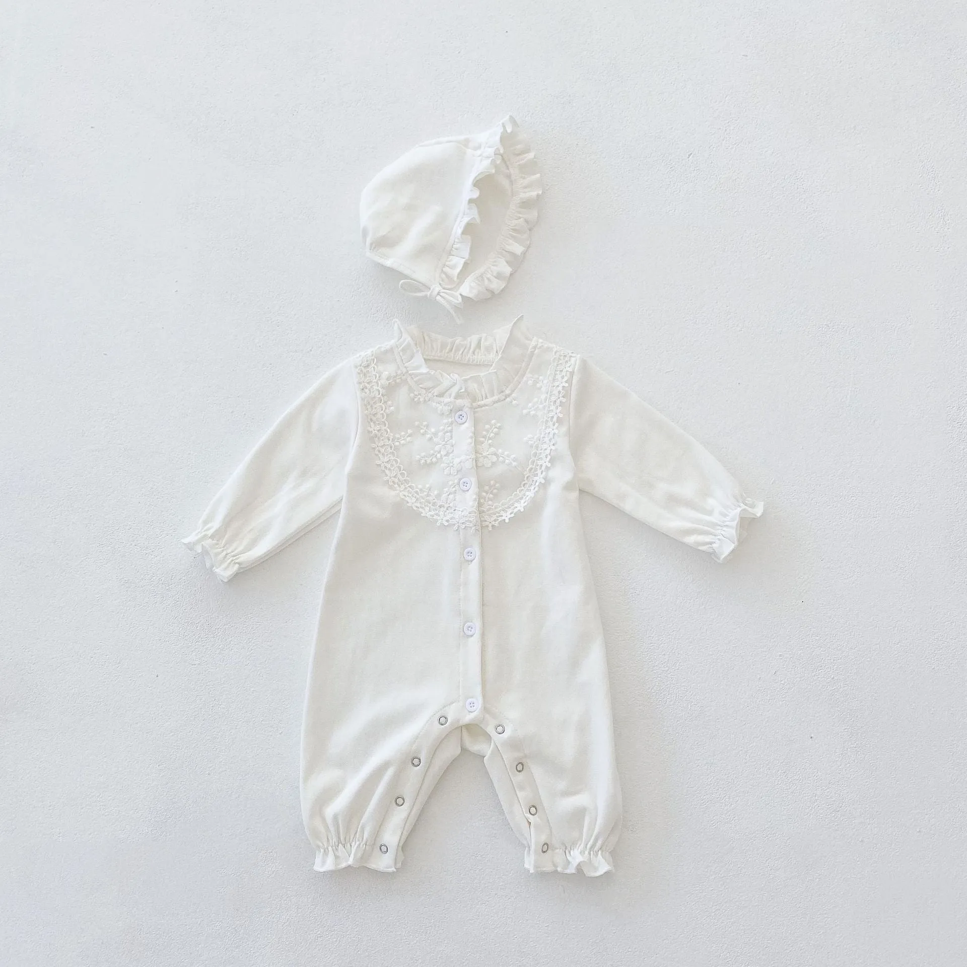 Beige knitted cotton baby jumpsuit with wooden ear collar and lace, long sleeves, hood, on a neutral background