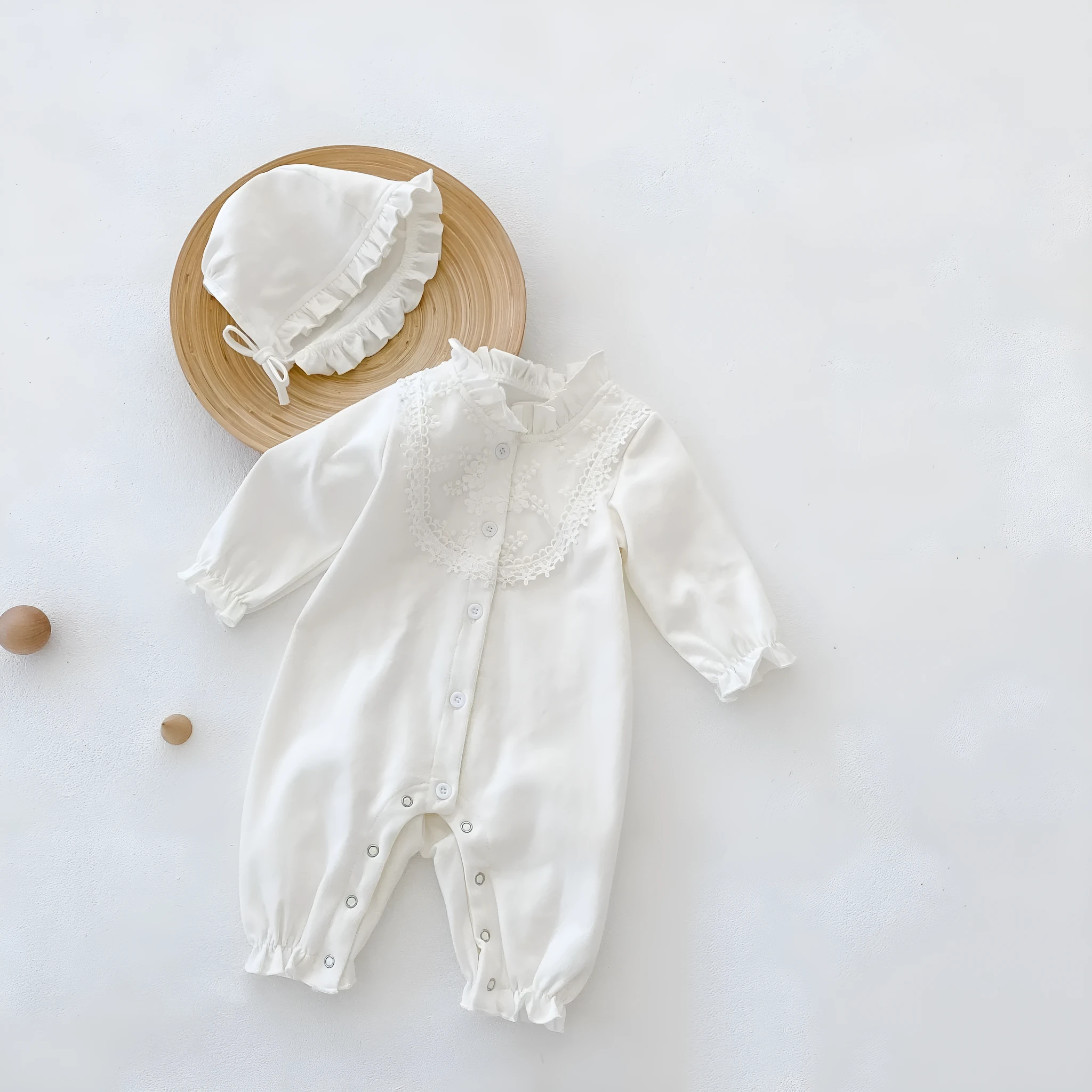 Beige knitted cotton baby jumpsuit with wooden ear collar and lace, long sleeves, hood, on a neutral background
