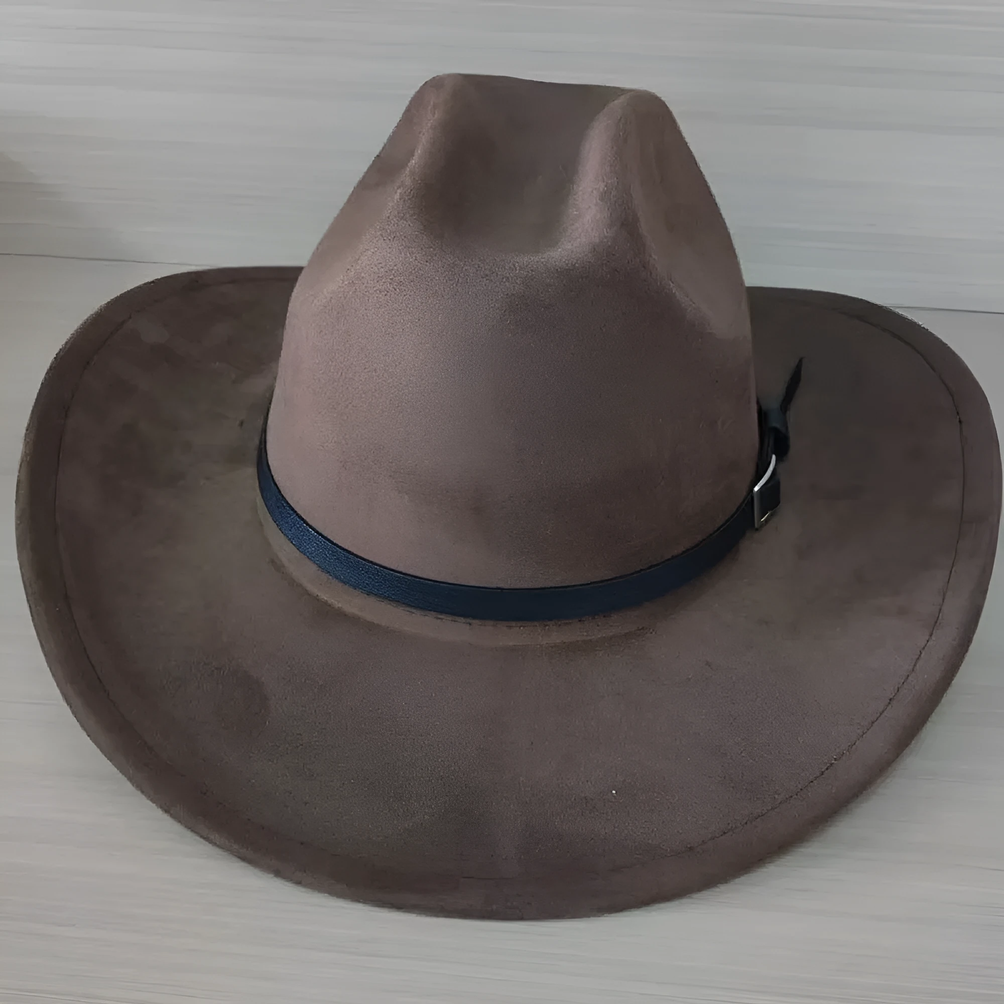 Brown leather velvet cowboy hat with curved brim and conical crown on a wooden post.