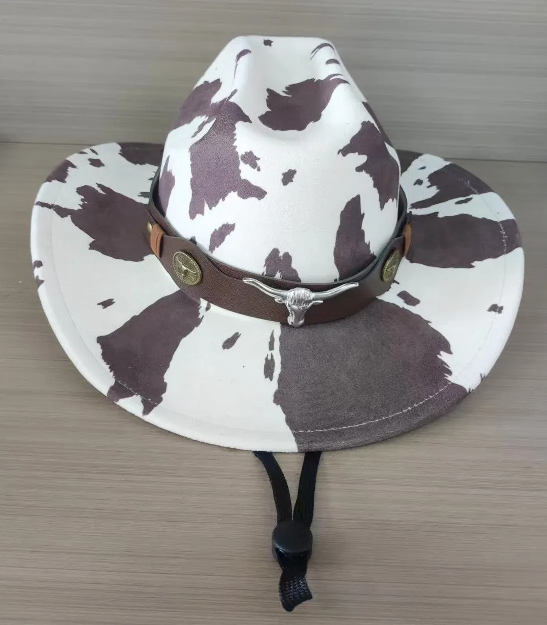 Brown leather velvet cowboy hat with curved brim and conical crown on a wooden post.