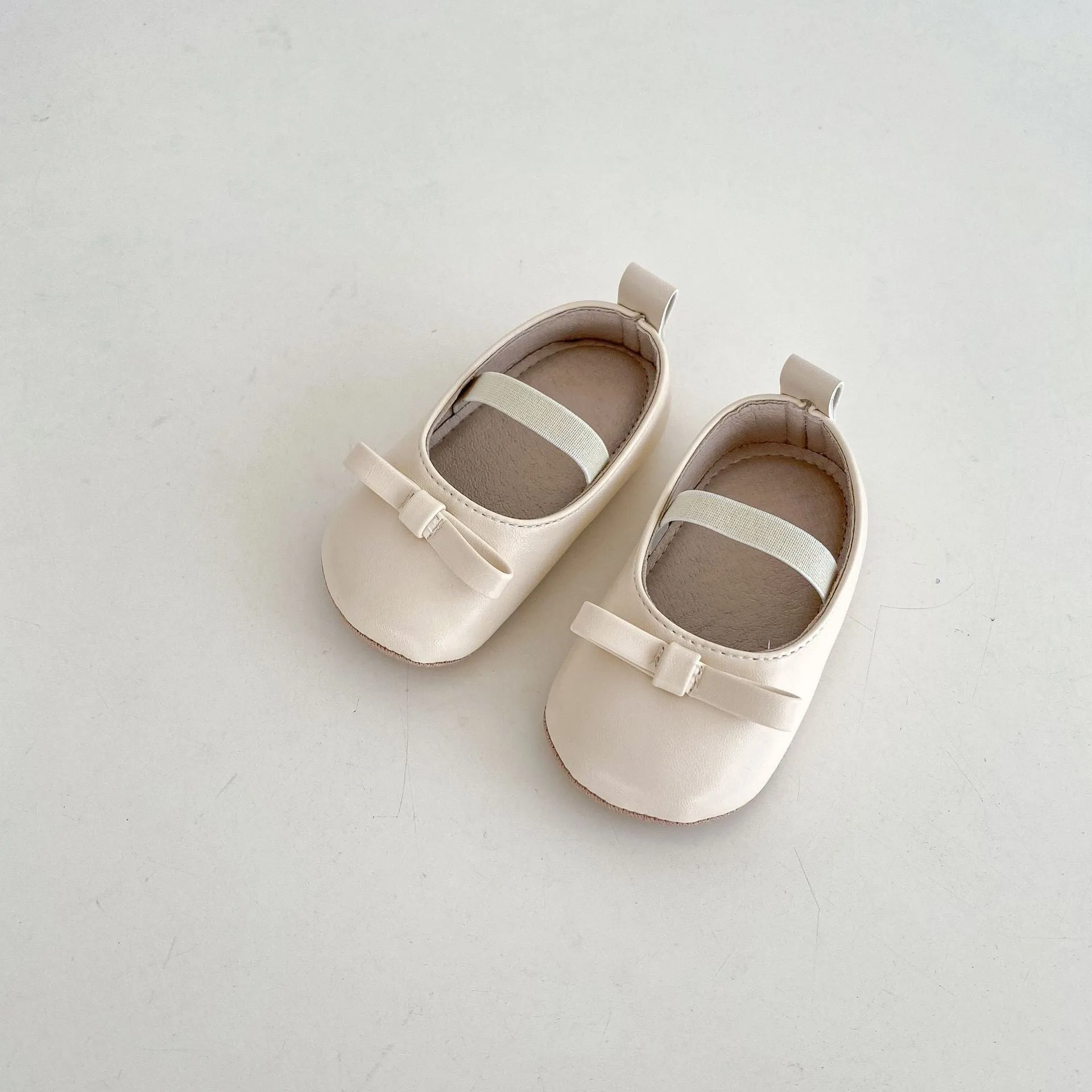 Women's soft non-slip PU low top baby shoes in black with bow detail on white background
