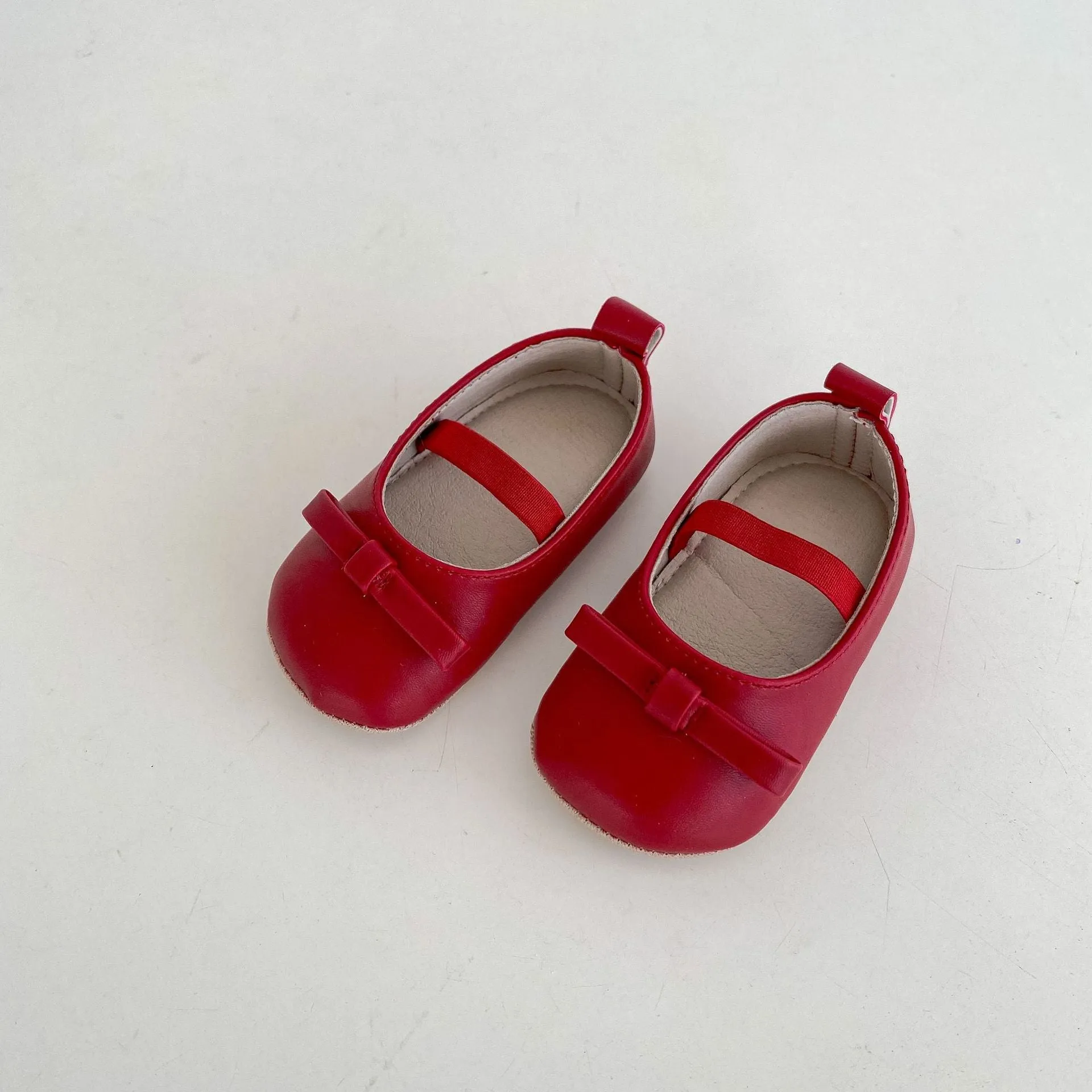 Women's soft non-slip PU low top baby shoes in black with bow detail on white background