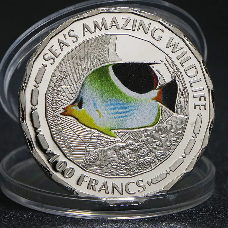 Set of eight silver plated commemorative coins with tropical fish and marine animal designs, 40mm diameter, in acrylic box