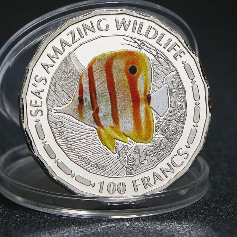 Set of eight silver plated commemorative coins with tropical fish and marine animal designs, 40mm diameter, in acrylic box
