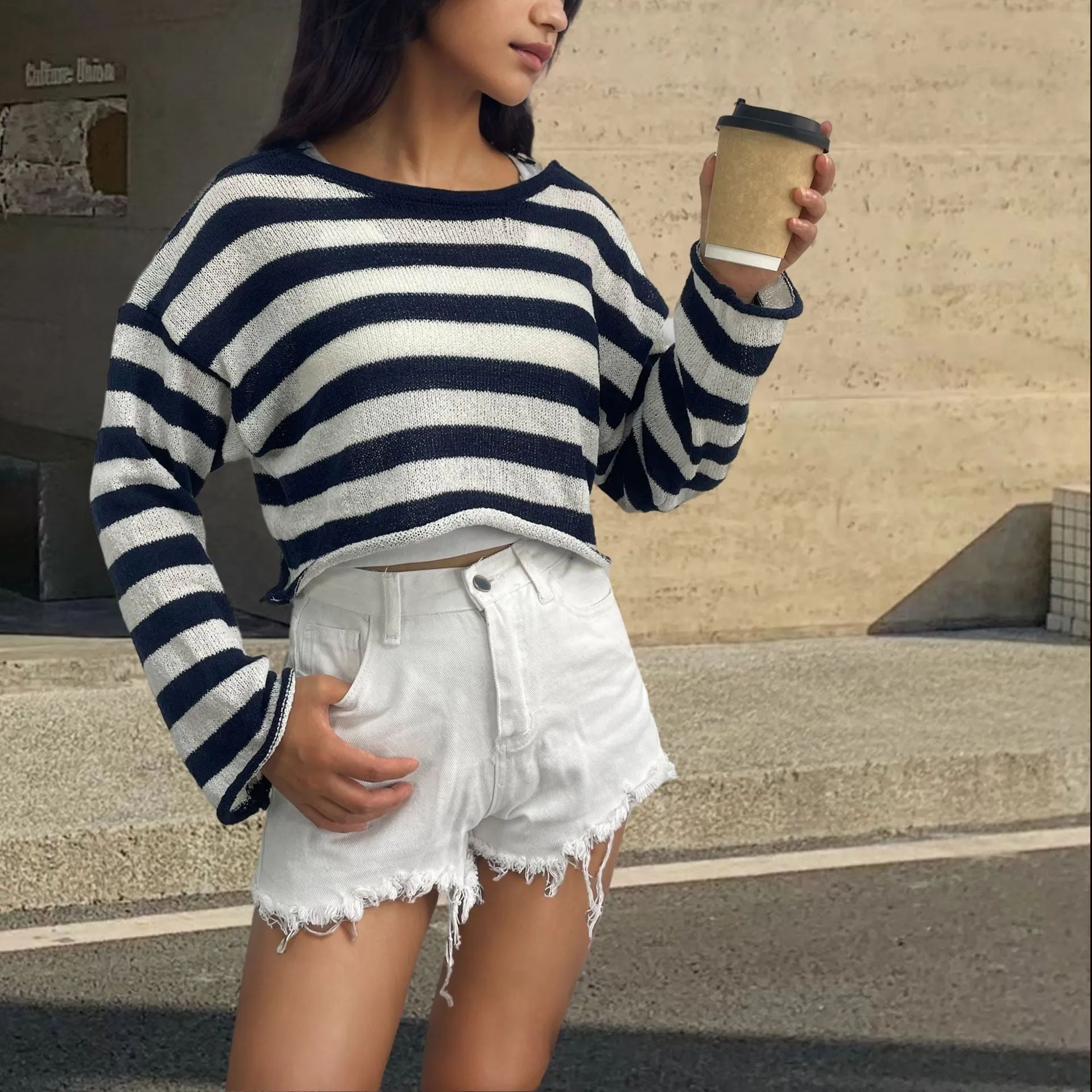 A woman wearing a cropped black and white striped long-sleeved sweater with a front and back exposed-navel design.