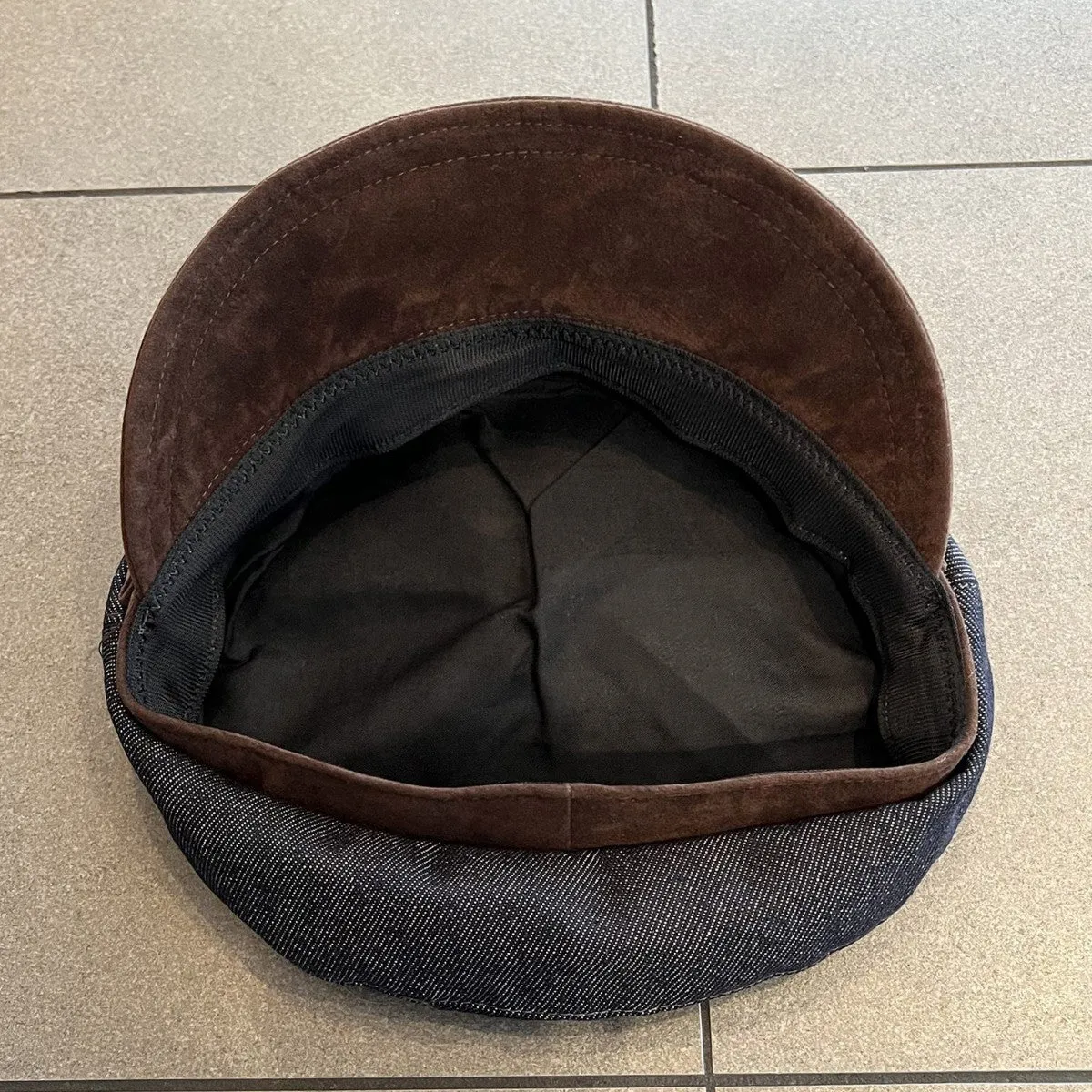 Dark blue denim octagonal newsboy flat cap with an adjustable strap, shown with a contrasting brown brim.