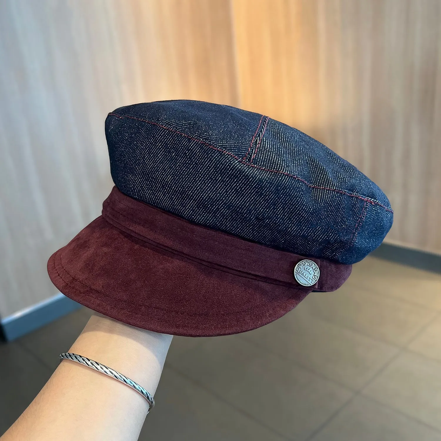 Dark blue denim octagonal newsboy flat cap with an adjustable strap, shown with a contrasting brown brim.