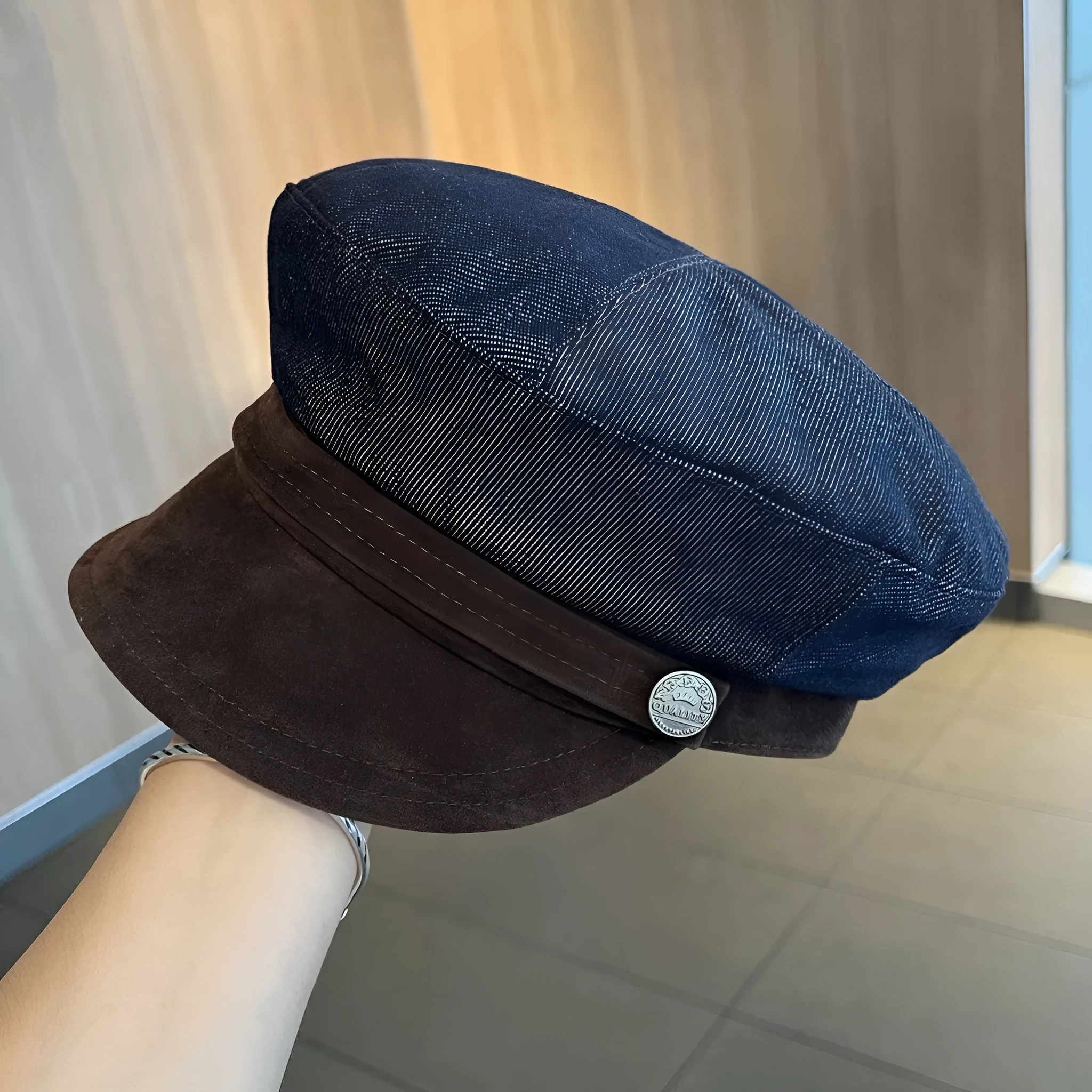 Dark blue denim octagonal newsboy flat cap with an adjustable strap, shown with a contrasting brown brim.