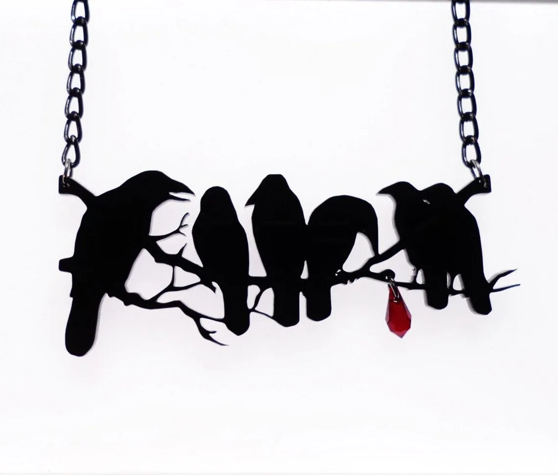 Black Gothic crow necklace with electroplated finish and cross chain on dark background