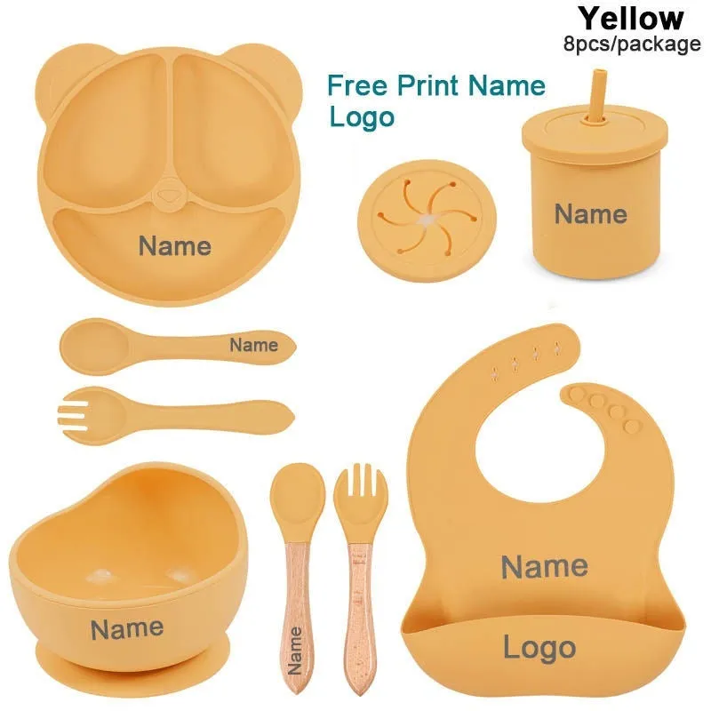 Children's silicone tableware set with cat ear cup in beige, blue and other colours on a table