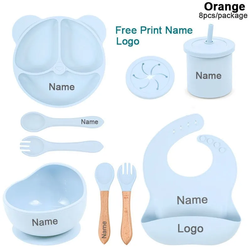 Children's silicone tableware set with cat ear cup in beige, blue and other colours on a table
