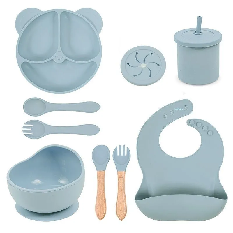 Children's silicone tableware set with cat ear cup in beige, blue and other colours on a table