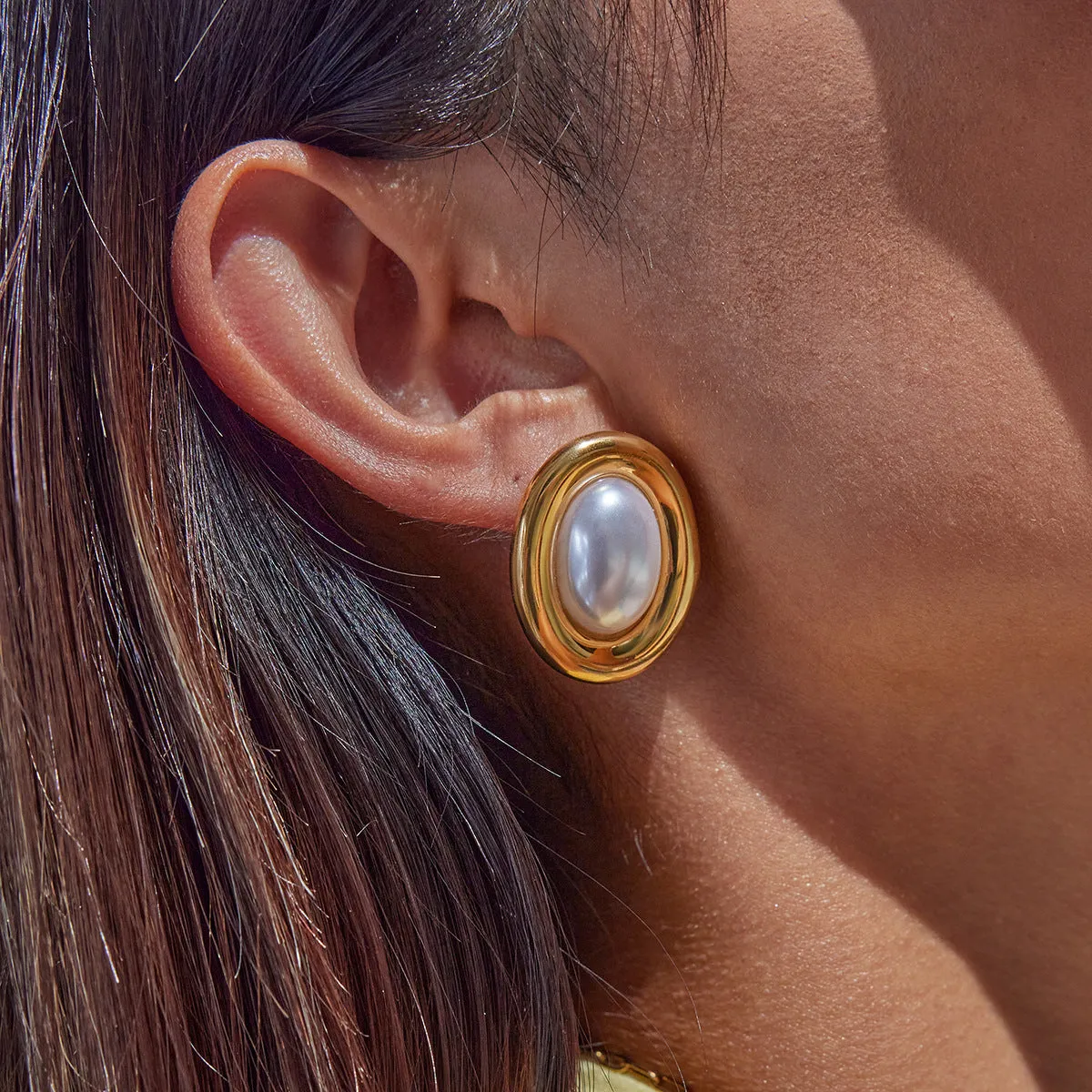 Close-up of a pair of women's stainless steel vintage pearl ear studs with a silver-toned post on a white background.