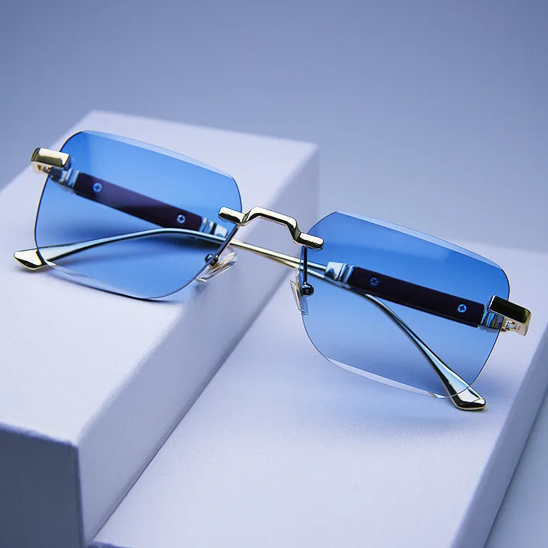 Frameless edge-cut sunglasses with gold frame, wood grain legs, and gradient grey lenses on a neutral background