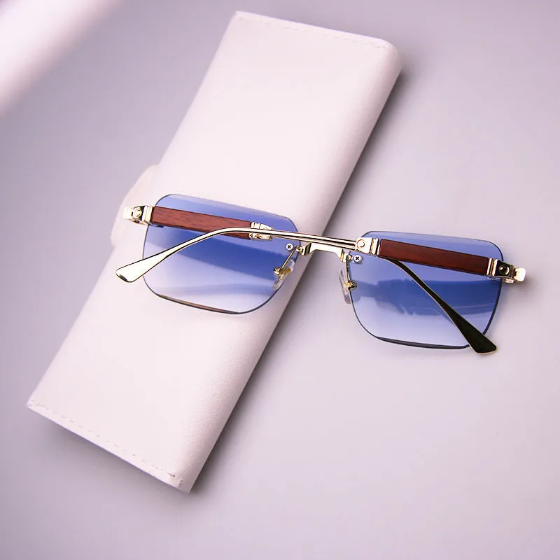 Frameless edge-cut sunglasses with gold frame, wood grain legs, and gradient grey lenses on a neutral background