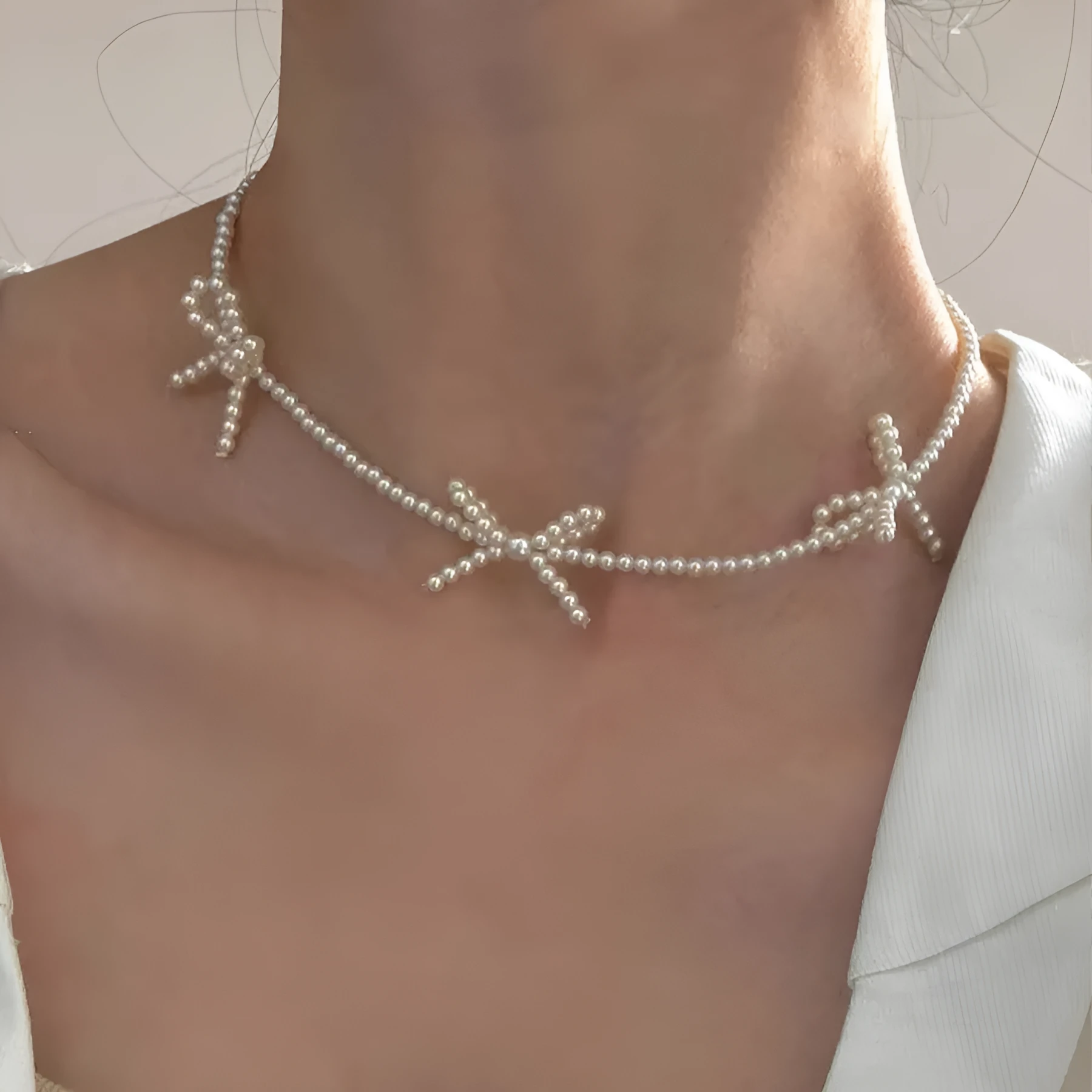 White bow pearl necklace with geometric clasp on woman at clavicle length