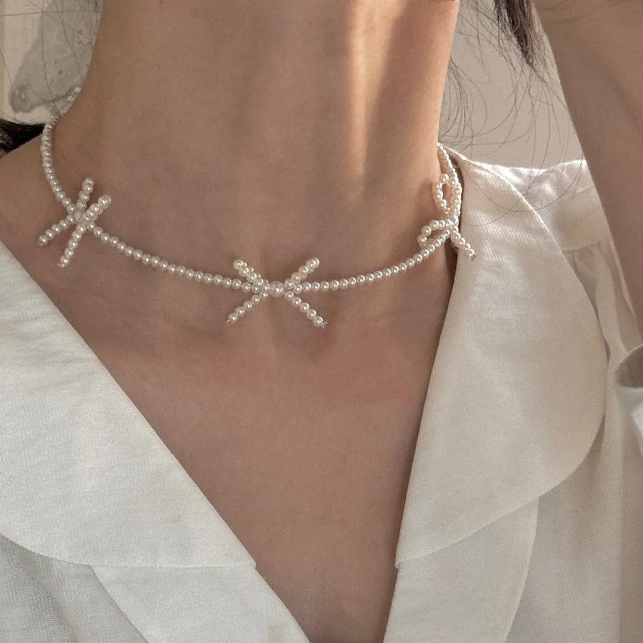 White bow pearl necklace with geometric clasp on woman at clavicle length
