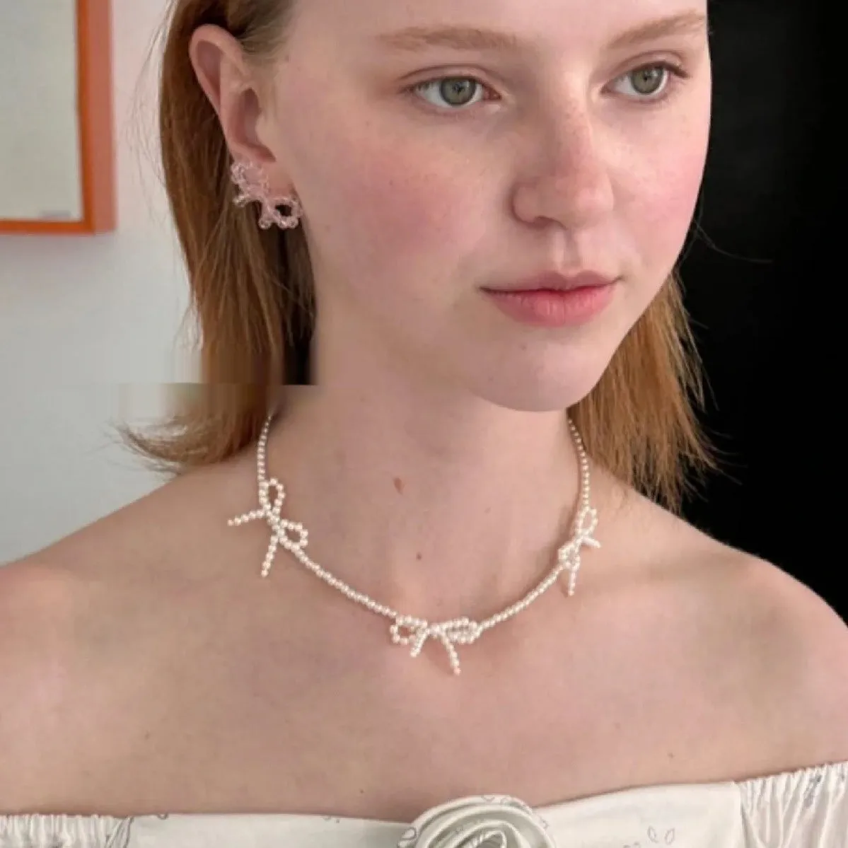 White bow pearl necklace with geometric clasp on woman at clavicle length