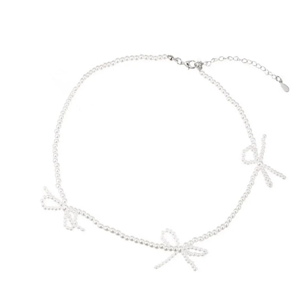 White bow pearl necklace with geometric clasp on woman at clavicle length