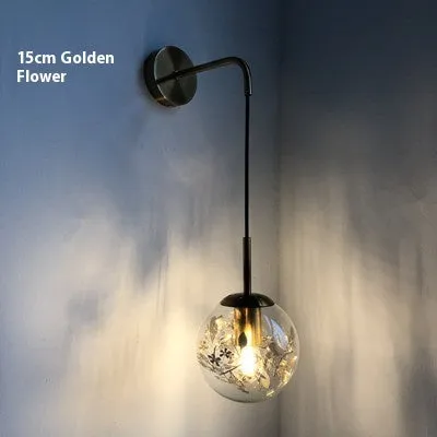 Modern golden flower glass wall lamp mounted beside a bed.