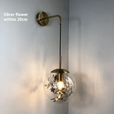Modern golden flower glass wall lamp mounted beside a bed.