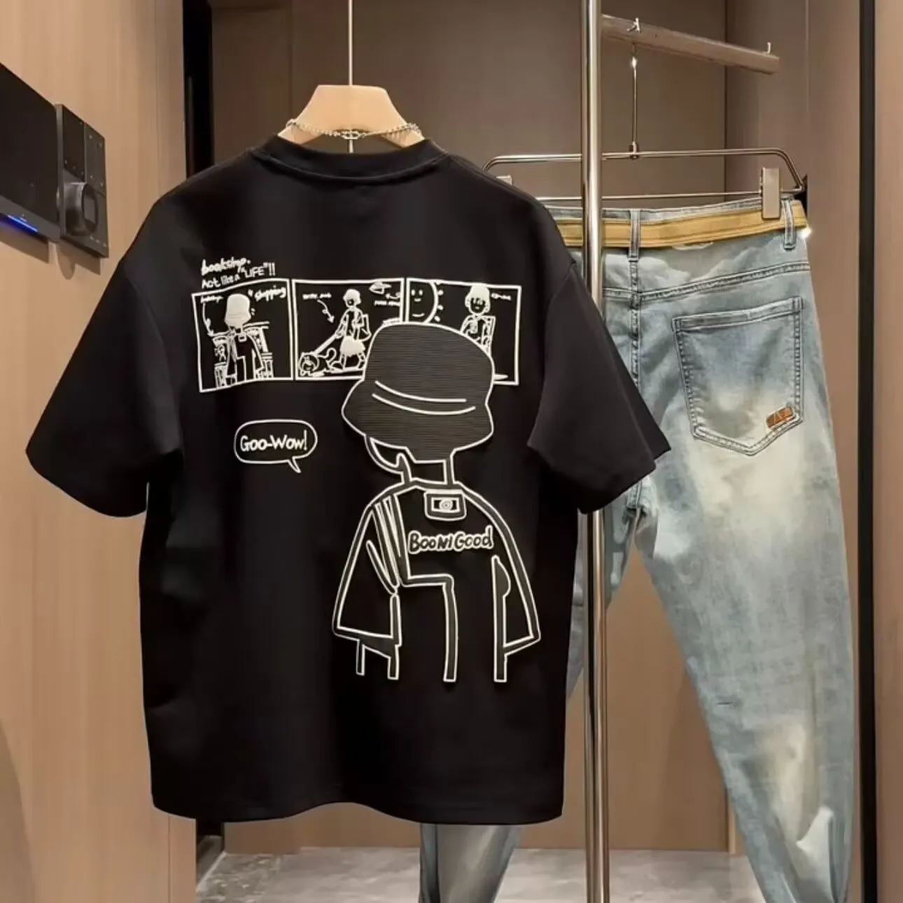 Men's black cotton t-shirt with a cartoon print, showing crew neck and short sleeve design on a hanger.
