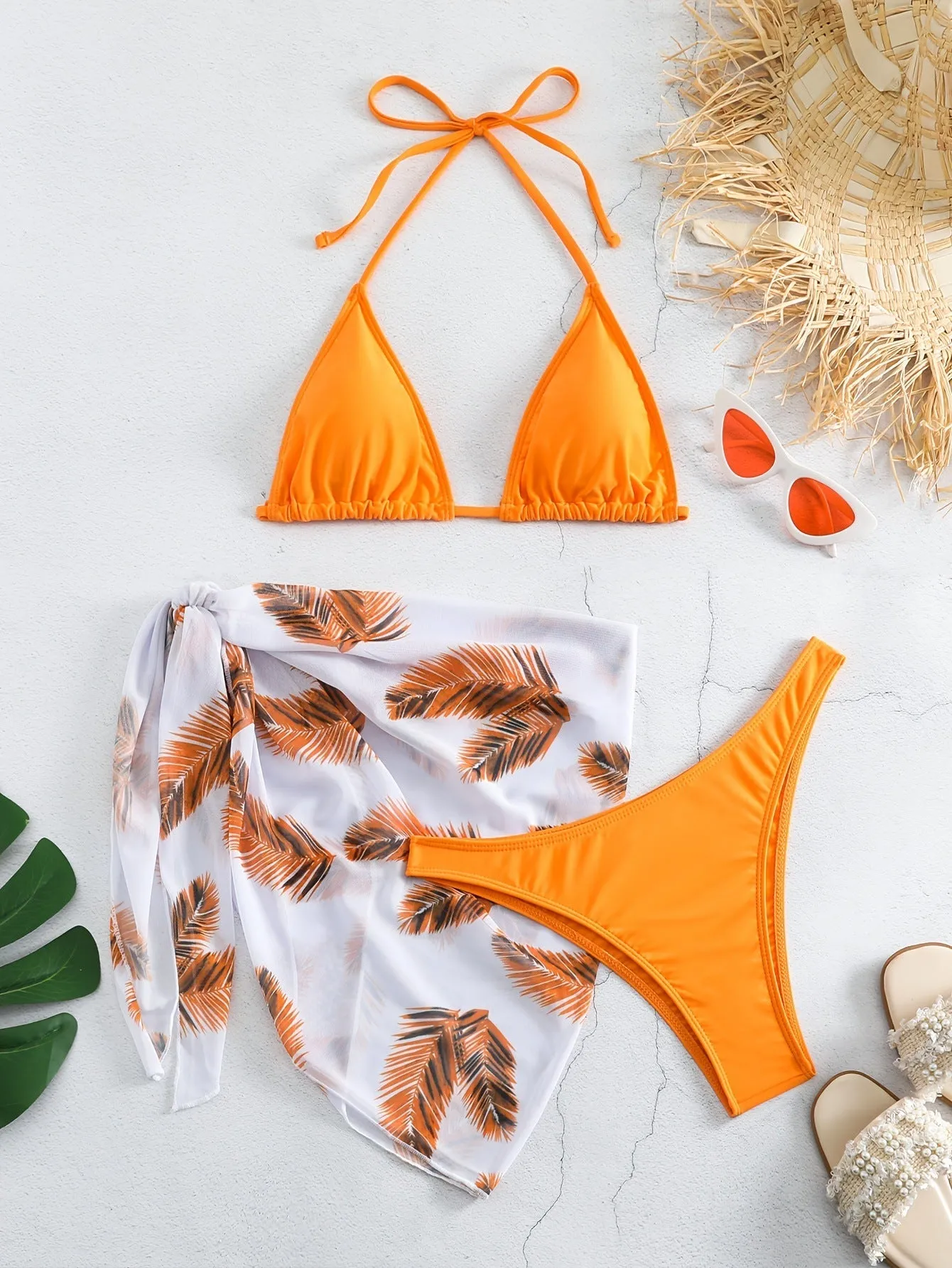 Orange three-piece bikini swimsuit set with a printed gauze skirt on a white background