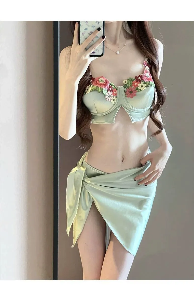 Green women's three-piece bikini swimsuit set with triangle top, briefs, and matching skirt