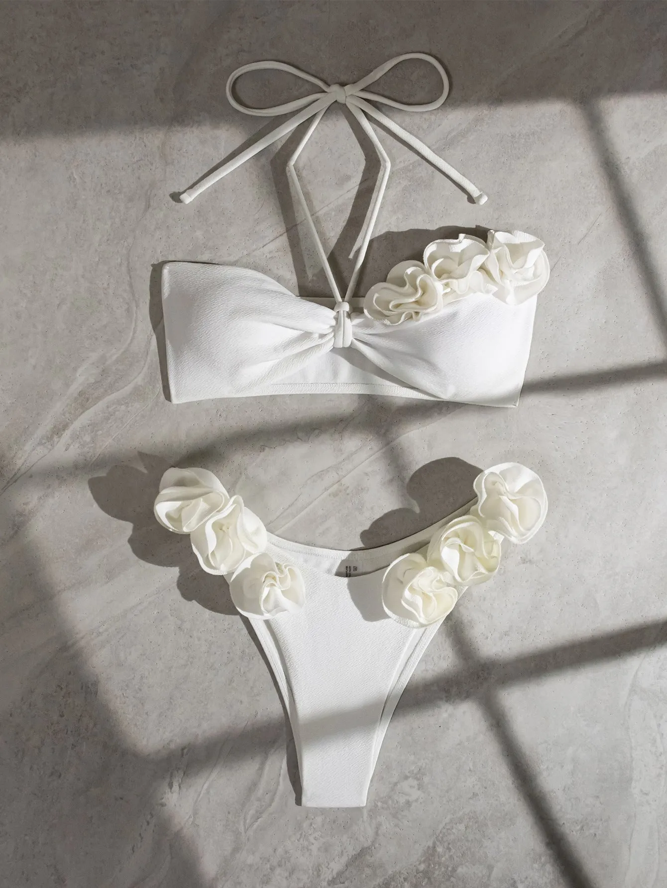 White women's halter lace-up swimsuit with three-dimensional floral design and briefs