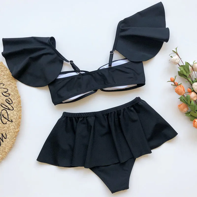 Women's red and black three-piece flounced bikini swimsuit on a hanger.