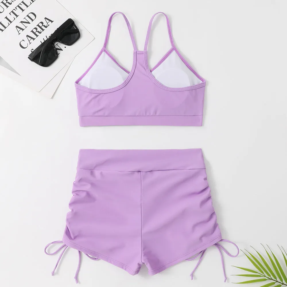 Women's black or purple high-waist split bikini swimsuit with sleeveless top and shorts.