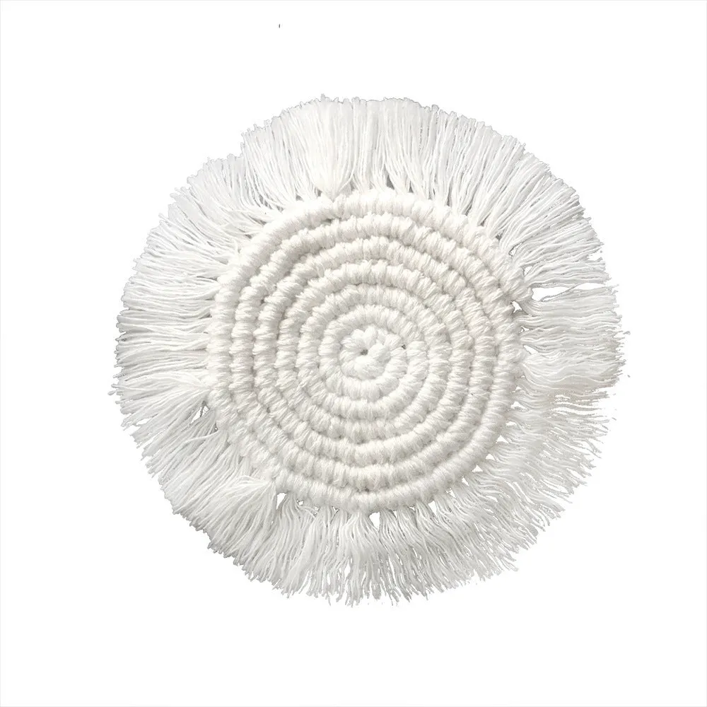 Hand-woven round beige cotton string coaster on a wooden table with a glass of water