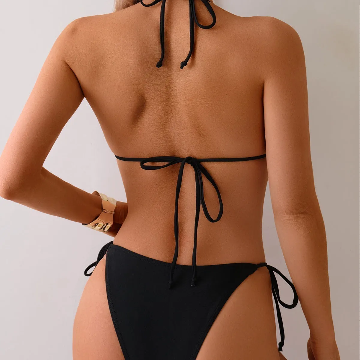 Black women's bikini swimsuit with metal bead detail and split design.