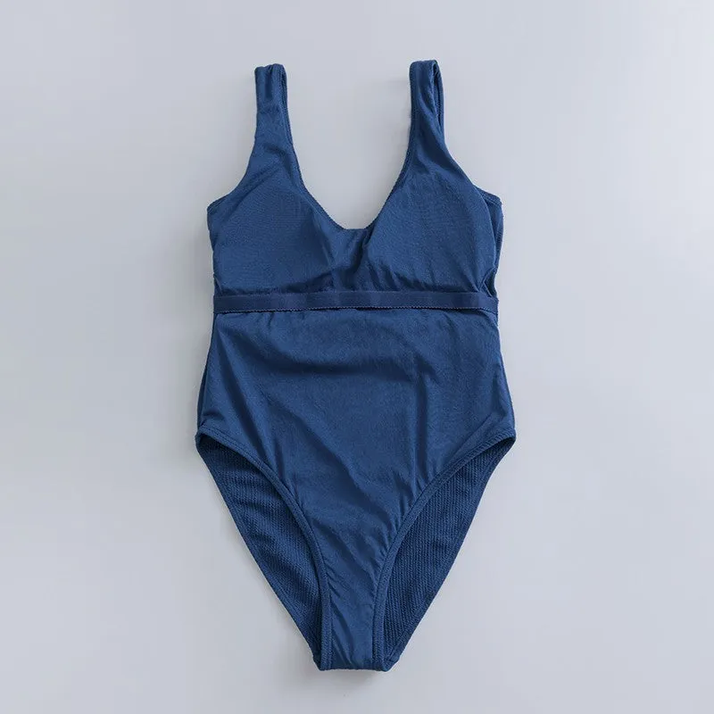 Navy blue one-piece women's swimsuit with a triangle neckline and slimming fit on a mannequin.