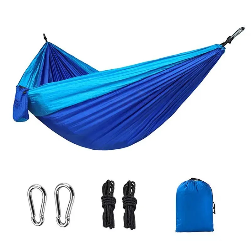 Blue nylon parachute cloth camping hammock hanging between two trees