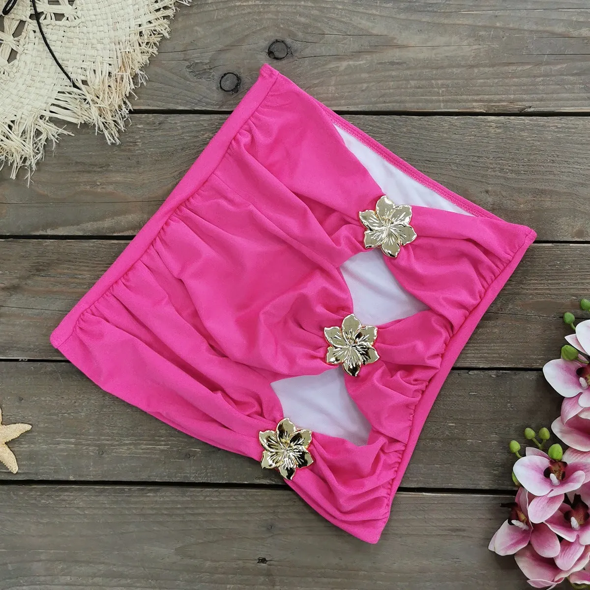 Women's black hollow-out tube top one-piece swimsuit with matching high-waist short skirt laid flat.