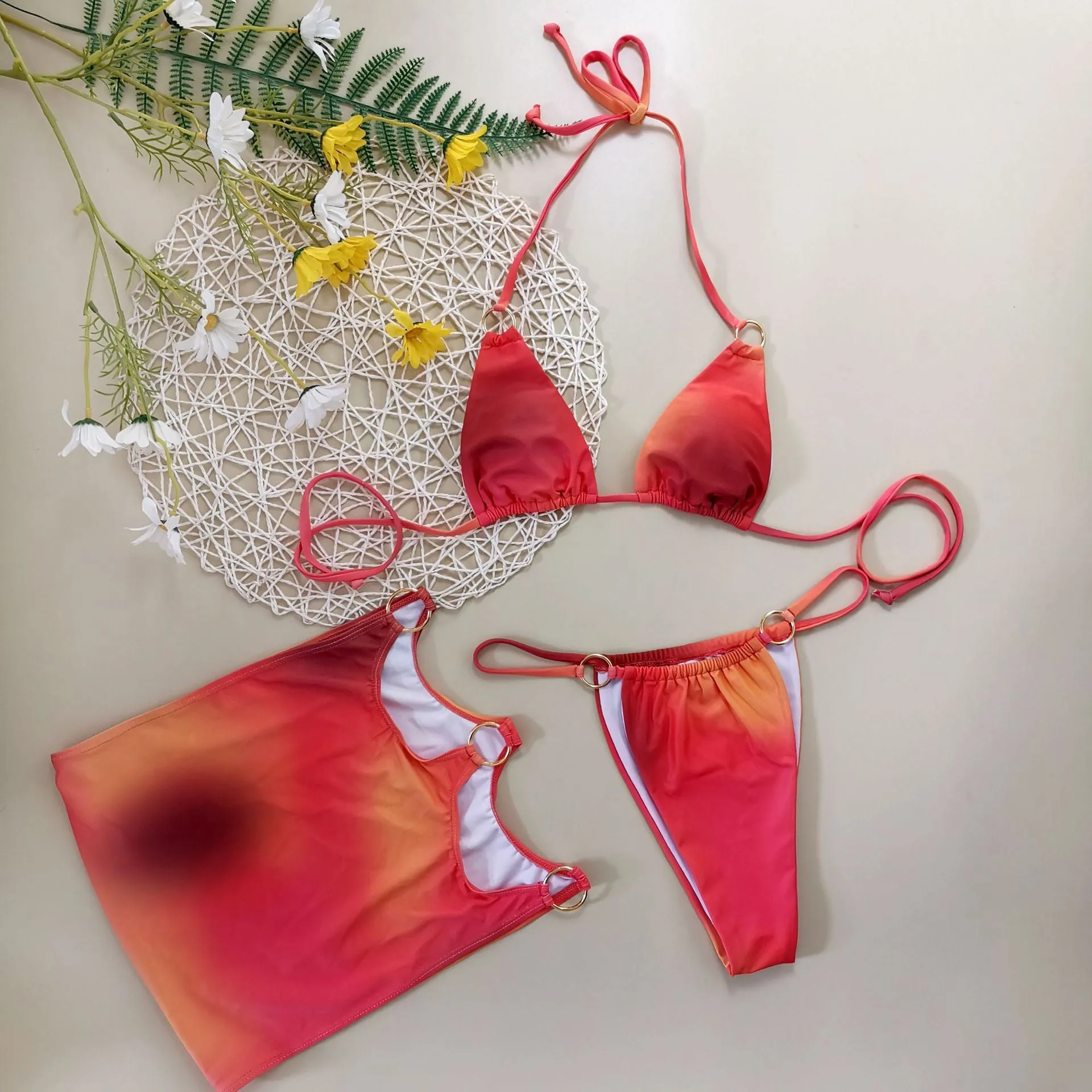 Tie-dye gradient three-piece halter bikini swimsuit set on a mannequin, showing top, high-waisted pants, and skirt.