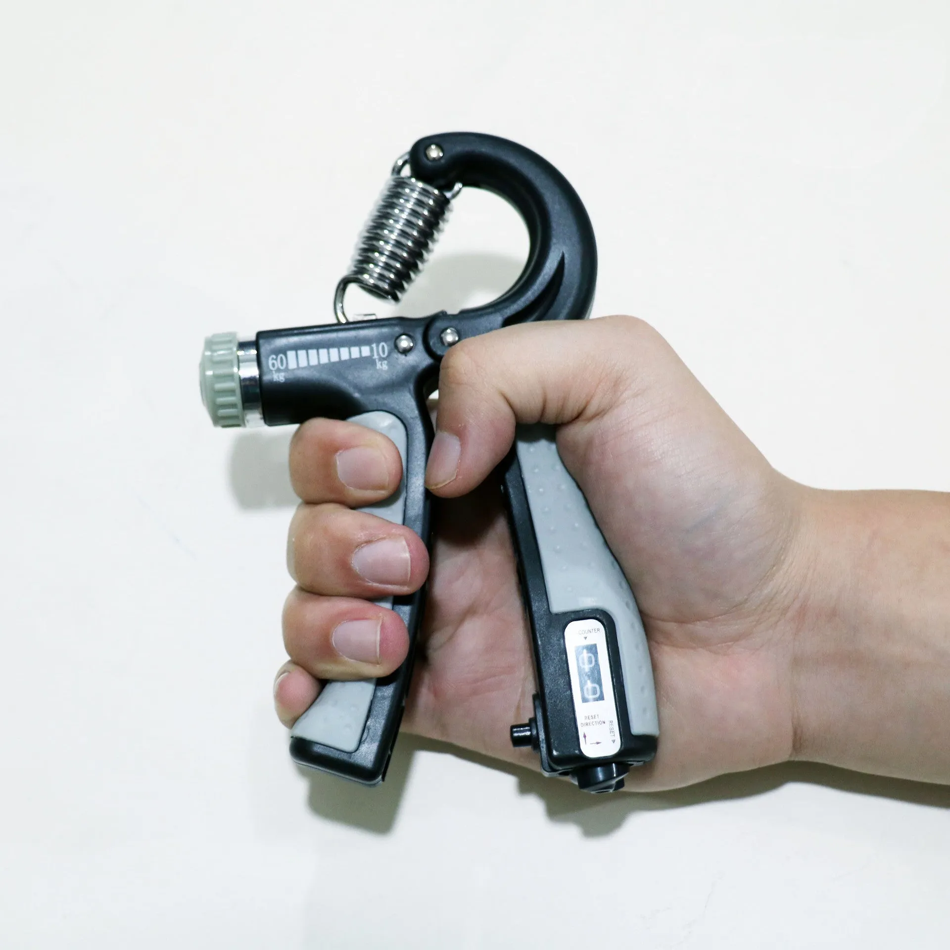 Adjustable hand grip with mechanical counter showing black ABS handles and stainless steel spring on white background
