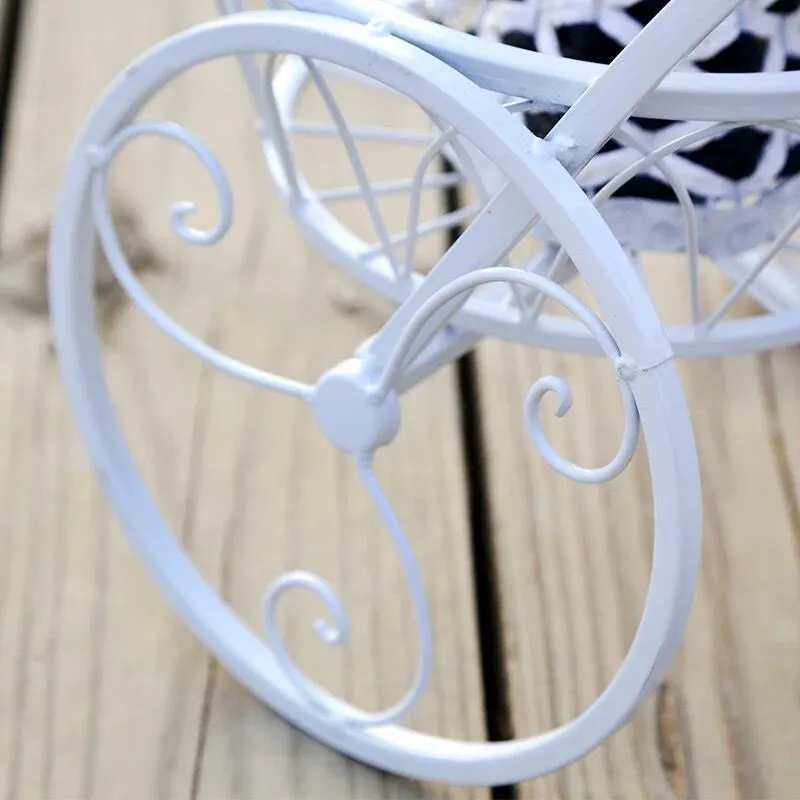 Black wrought iron tricycle plant stand with three round basket tiers and decorative scroll wheels