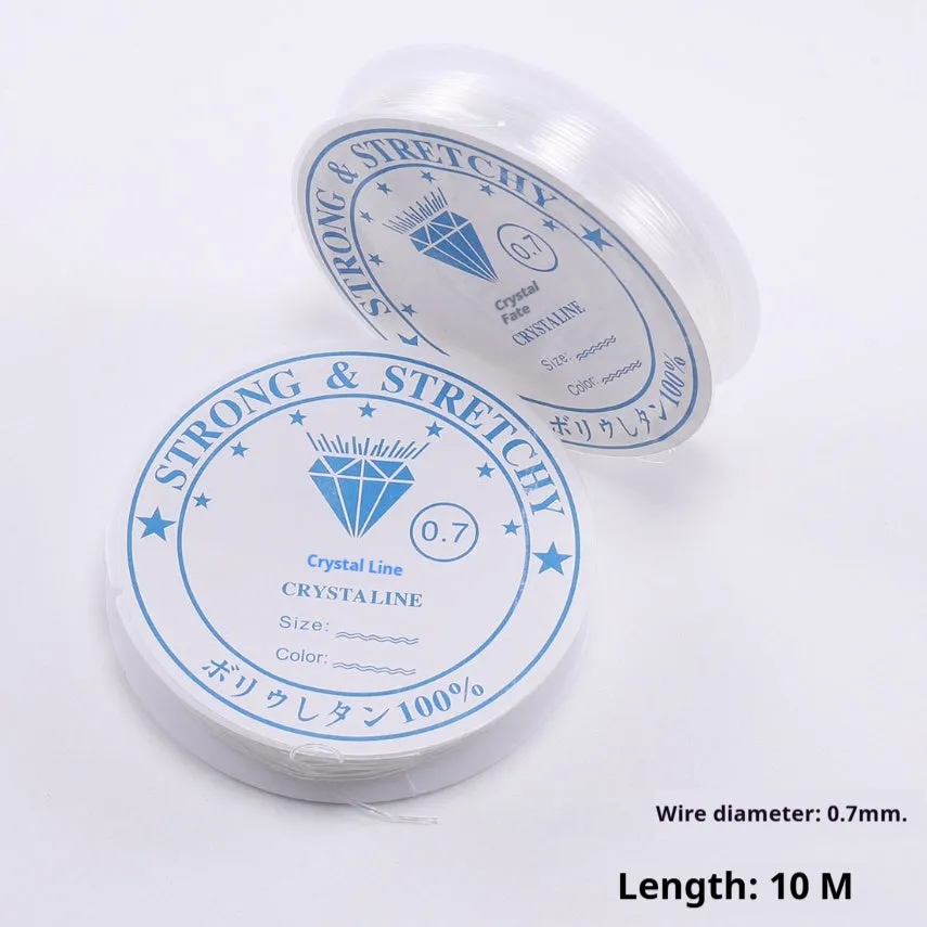 Spool of transparent white elastic cord for jewellery making on a craft table.