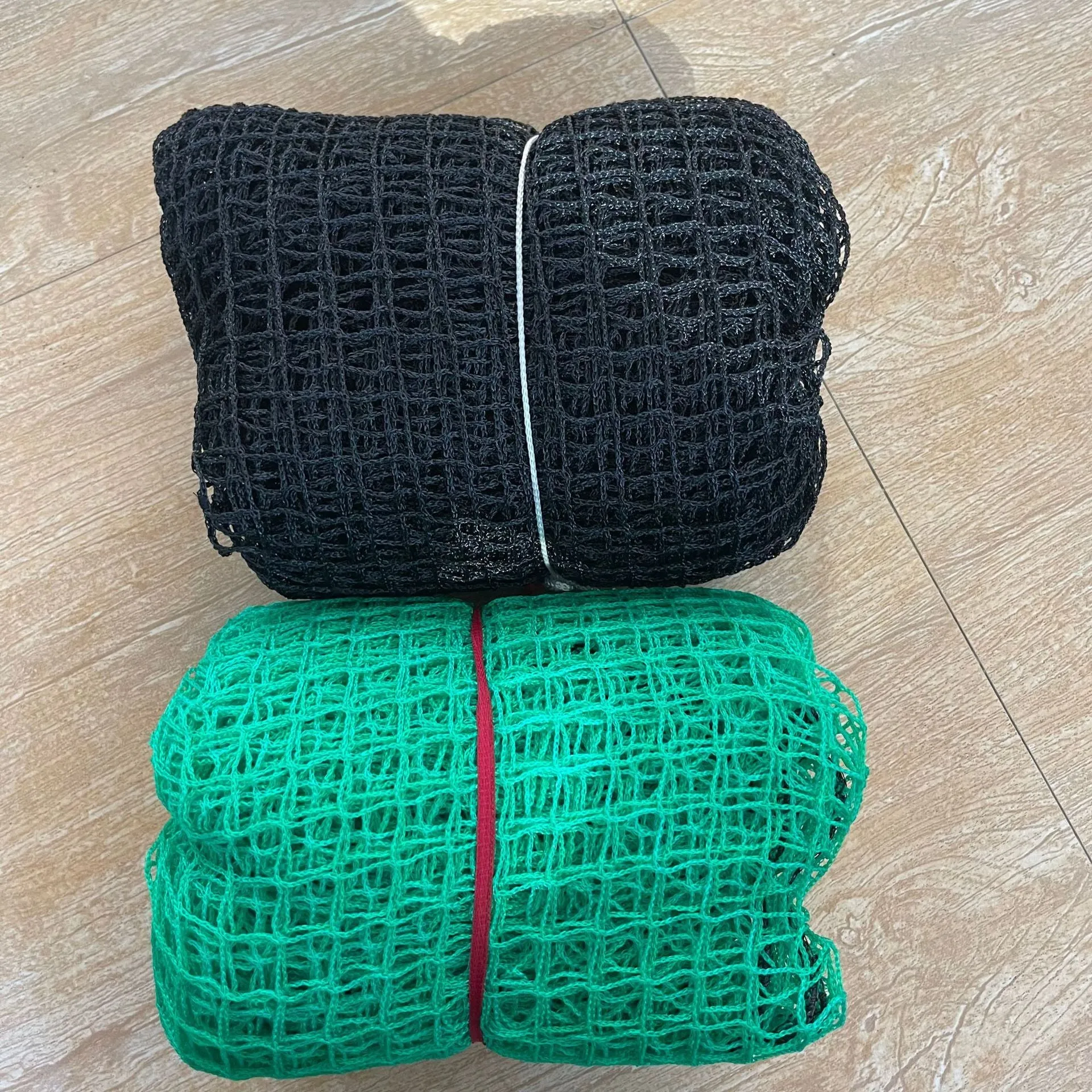 Polyethylene golf practice net in black on grass, with training balls visible