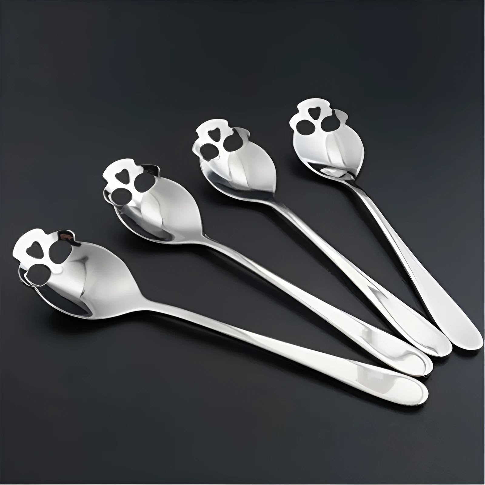 Stainless steel skull-shaped coffee mixing spoon on a dark surface