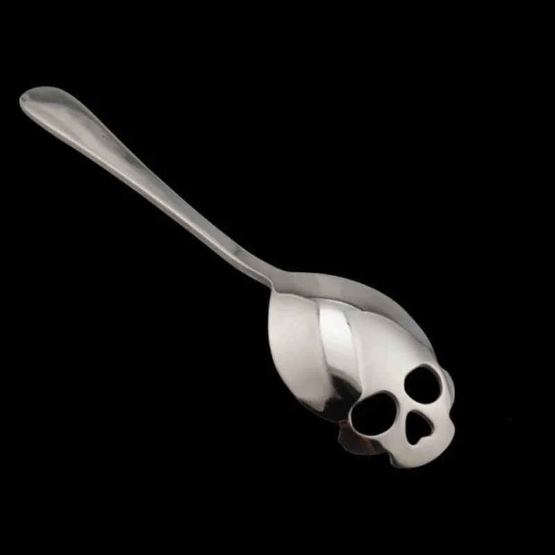 Stainless steel skull-shaped coffee mixing spoon on a dark surface