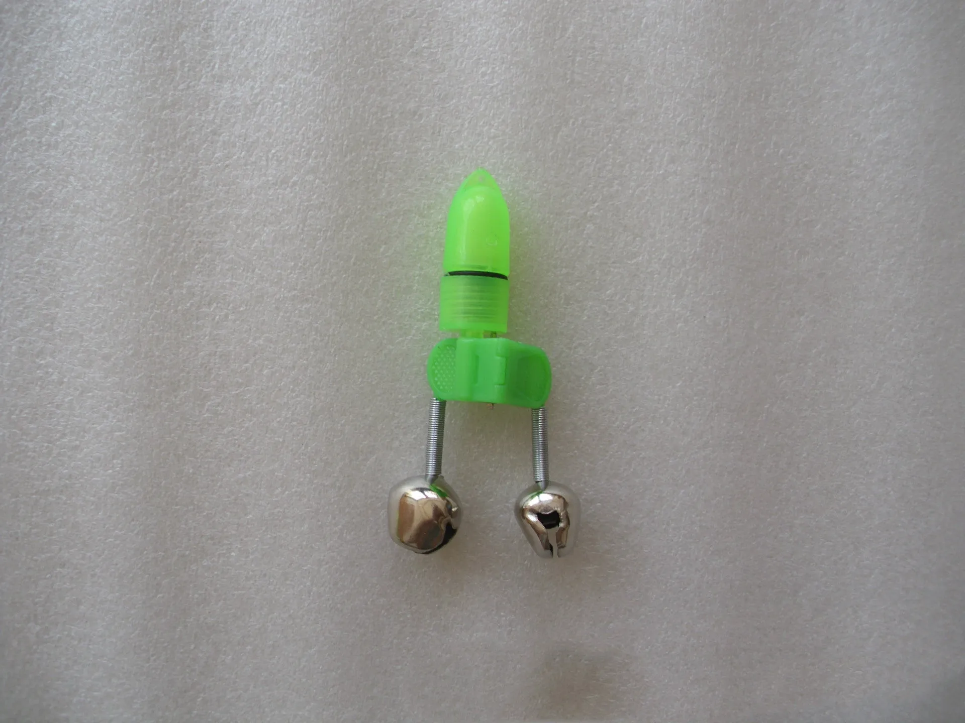 Two fishing bell bite alarms with LED lights, one green one red, clipped onto a fishing rod tip
