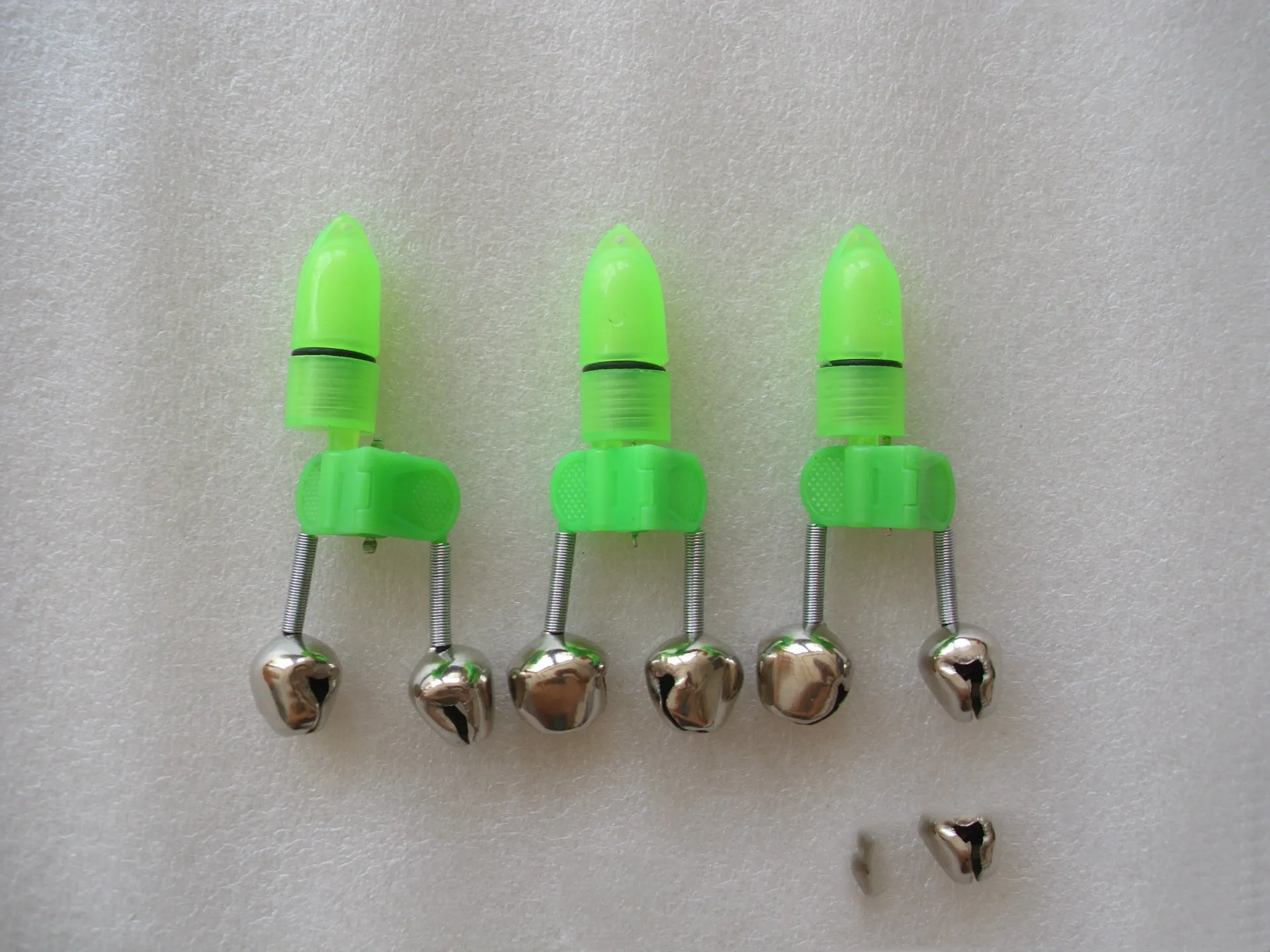 Two fishing bell bite alarms with LED lights, one green one red, clipped onto a fishing rod tip