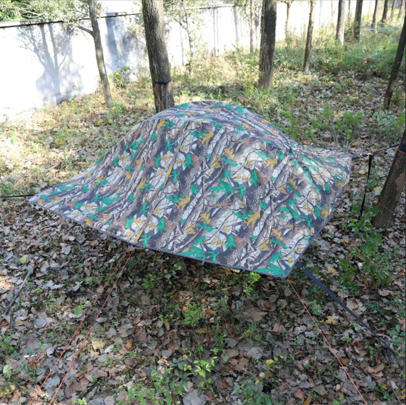 Self-driving tour camping hammock tent with aluminium pole and mosquito net suspended between trees in a forest setting