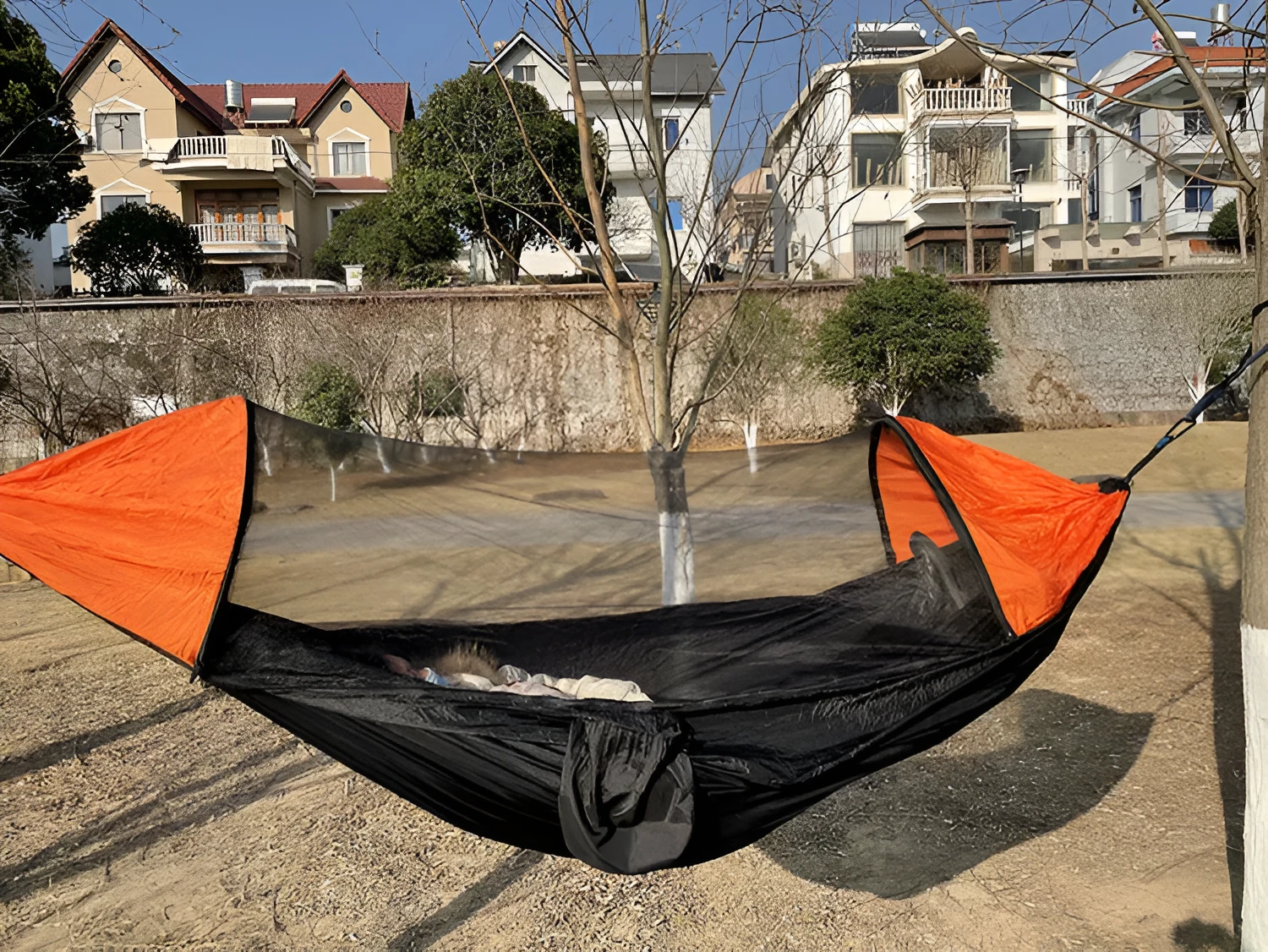 Automatic quick-opening double hammock with mosquito net and sun shades in Army Green Orange set up between trees outdoors
